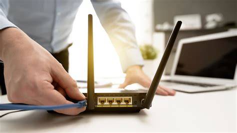 A person configuring a wireless router with a laptop nearby.